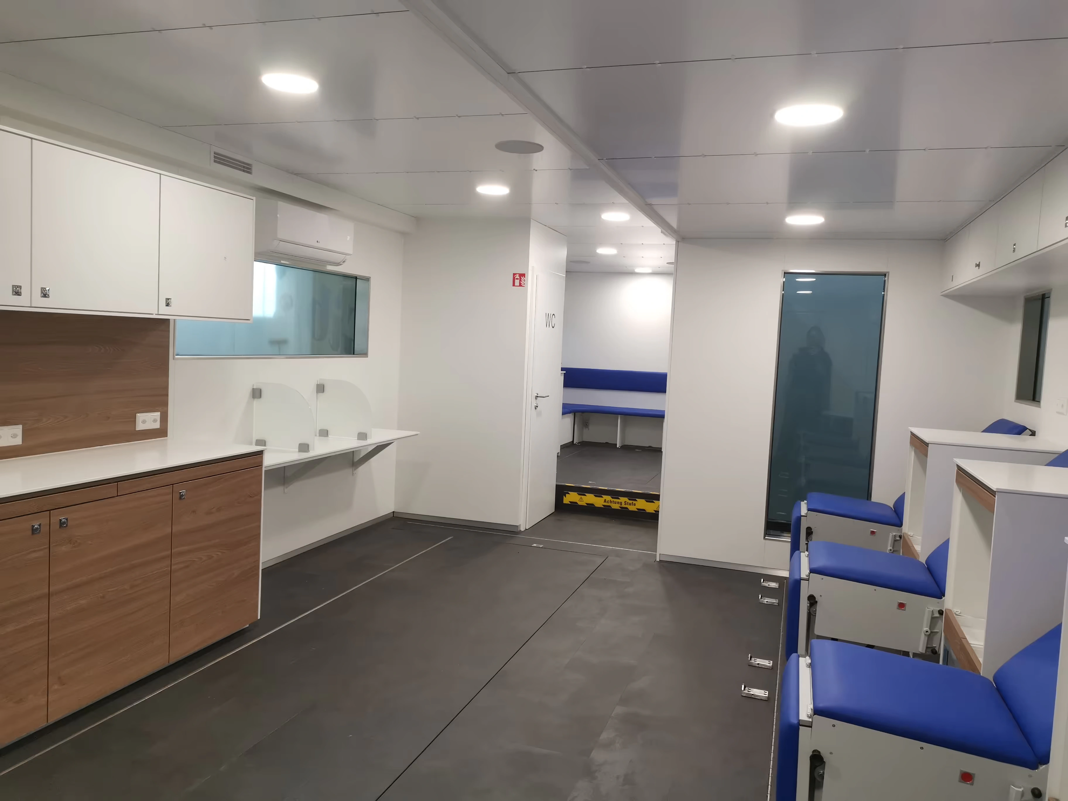 Mostradores de registro, almacenamiento integrado y asientos en el interior de una unidad móvil de extracción de sangre.